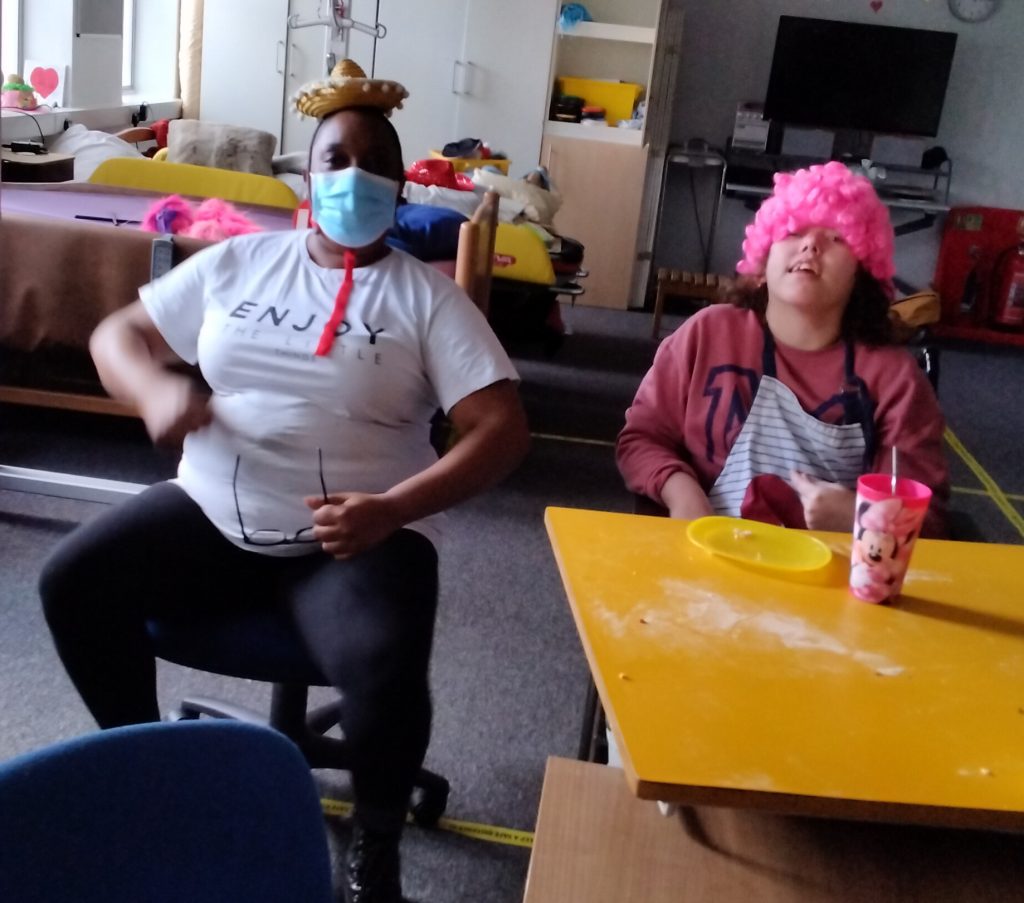 Female individual we support wearing a pink wig pictured with support staff