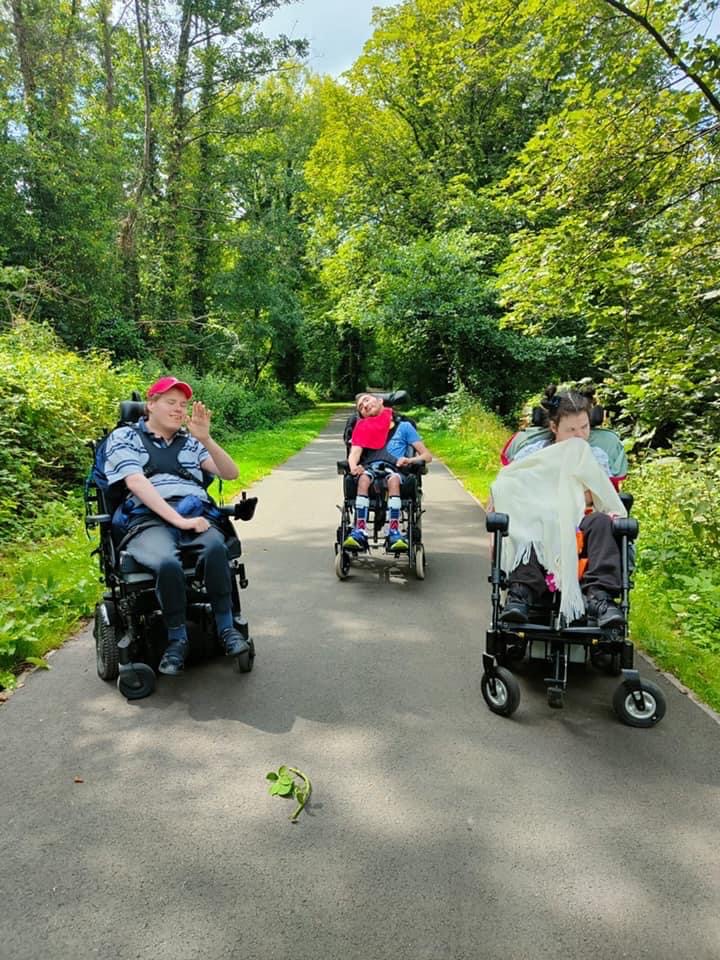 Group of wheelchair users outside on a forestry pathway