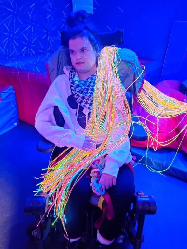Female individual seated in a sensory room holding sensory fibre optic