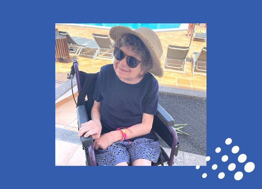 Steph from Roman House, Salutem Care and Education on holiday in Lanzarote, sitting in her wheelchair in the sunshine with a hat on.